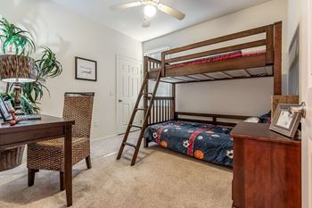 A room with a bunk bed, a desk, and a chair.